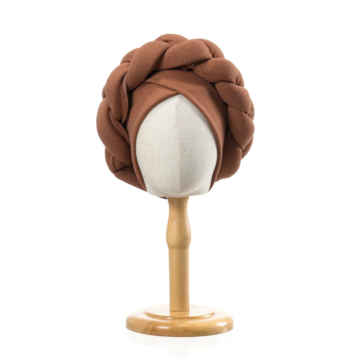 A brown braided turban cap displayed on a wooden mannequin stand.