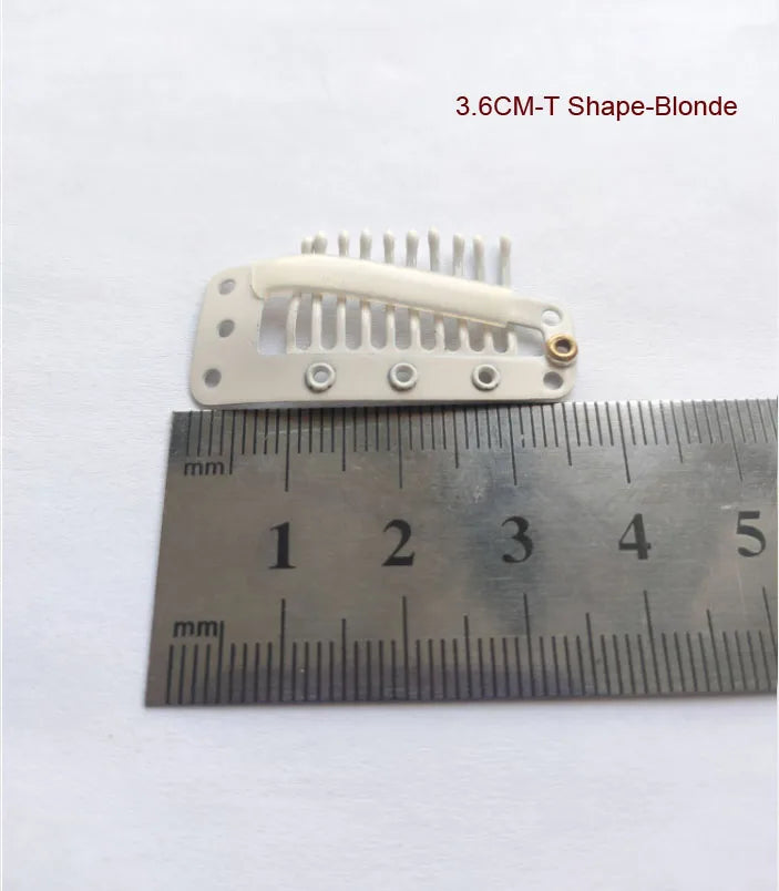Une pince pour extension de cheveux blonde en forme de T de 3,6 cm à côté d'une règle pour l'échelle.