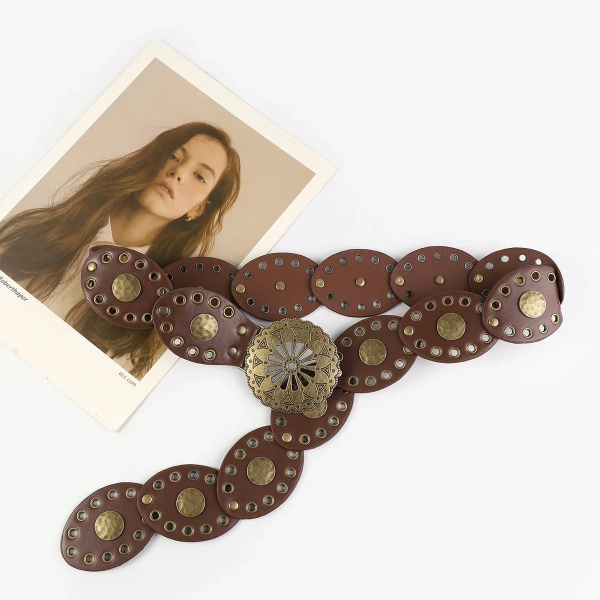 A brown leather belt featuring round, hollow metal buckles and a decorative brass centerpiece.