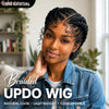 A young woman models a braided updo wig while wearing a denim shirt in a bright indoor setting.