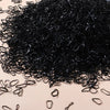 A pile of black disposable rubber hair ties scattered on a light surface.