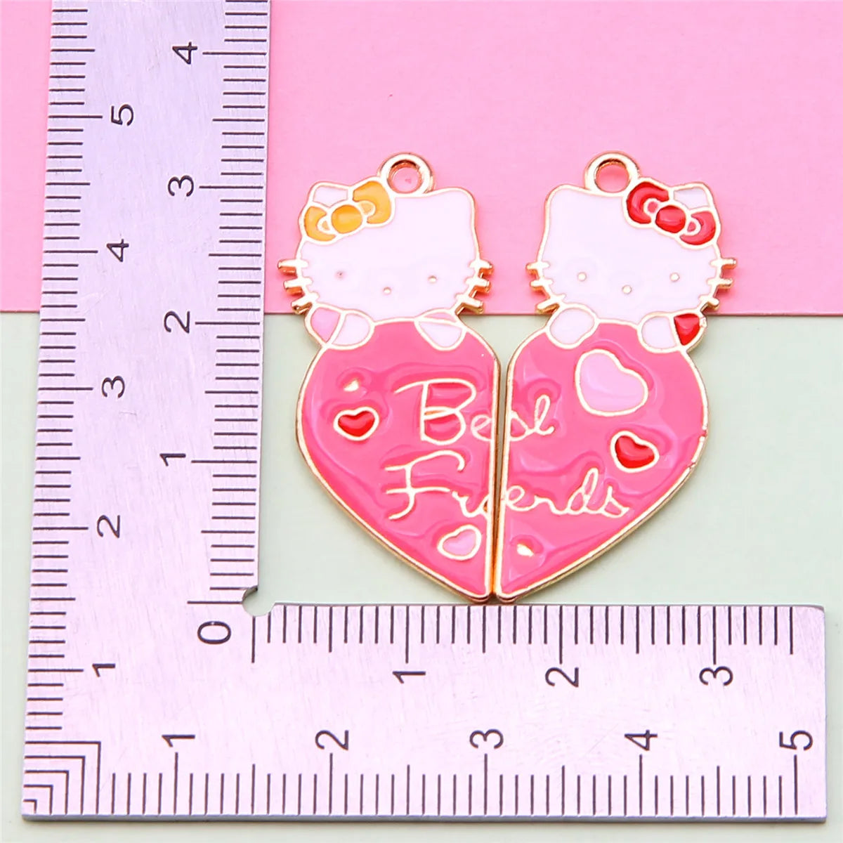 Un set de collares de amistad de esmalte rosa con colgantes de caras de gatos y la palabra 'Mejores Amigas' en fondo rosa.