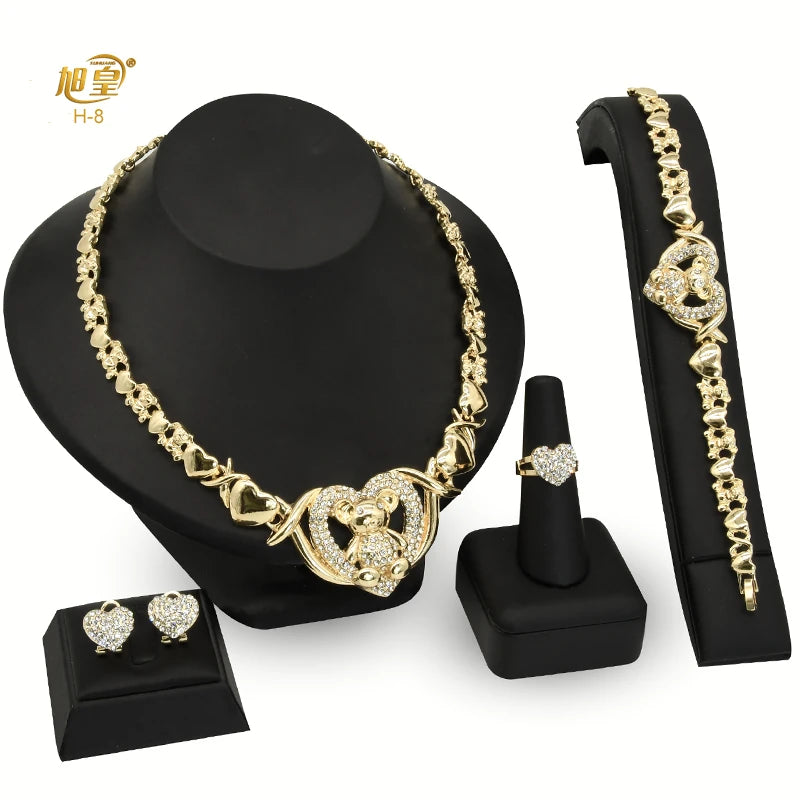 A set of 18K gold heart crystal jewelry including a necklace and an earring displayed on a black stand.