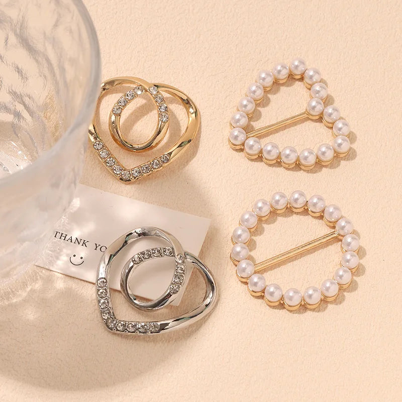 Gold and silver rhinestone and pearl decorative button clips arranged on a light background.