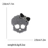 Broche de calavera con pedrería plateada y lazo, mide 2.8 cm de ancho y pesa 6.6g.
