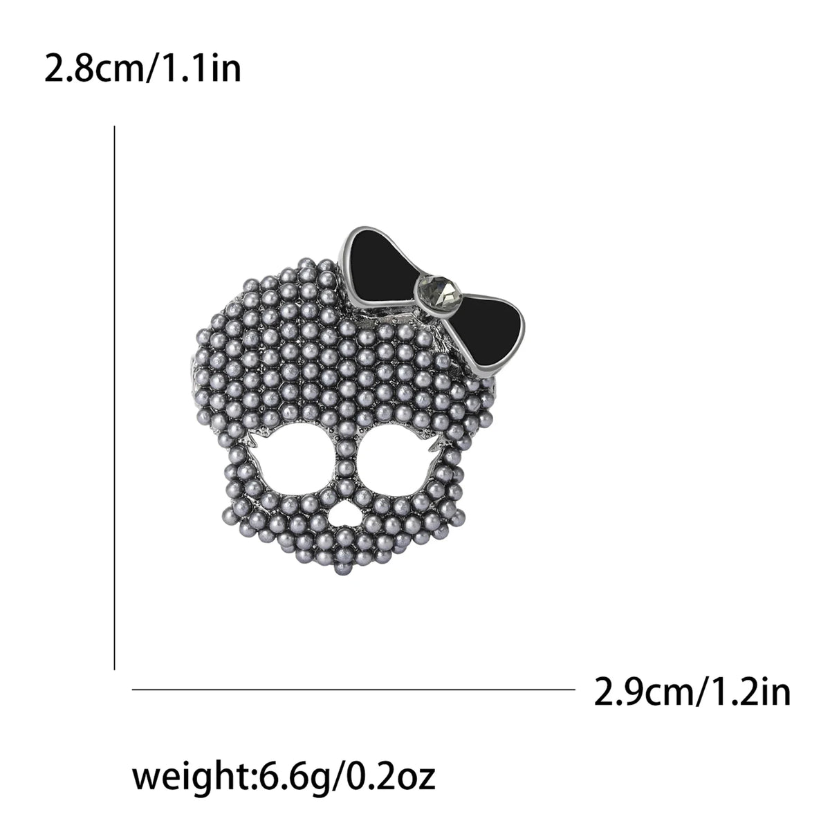 Broche de calavera con pedrería plateada y lazo, mide 2.8 cm de ancho y pesa 6.6g.