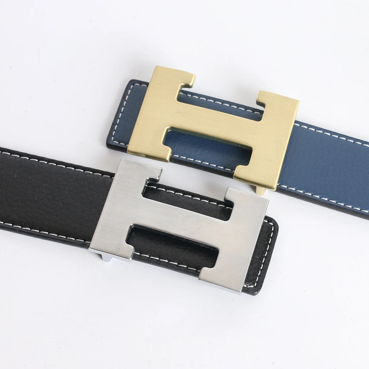 A close-up of a genuine leather dress belt for jeans featuring two buckles, one gold and one silver.