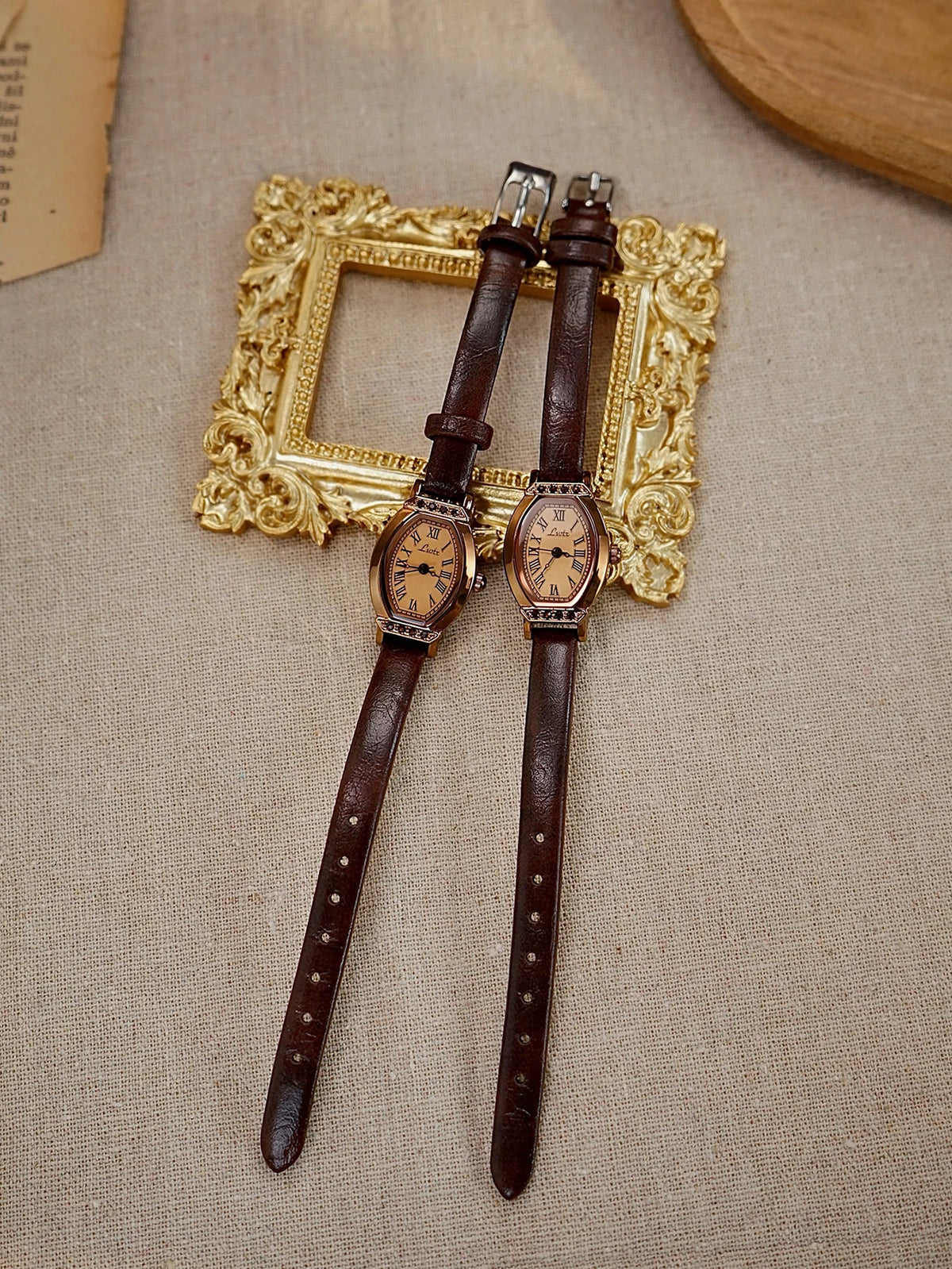 Reloj de correa de cuero marrón vintage con esfera dorada y decoración de strass, exhibido sobre tela clara.