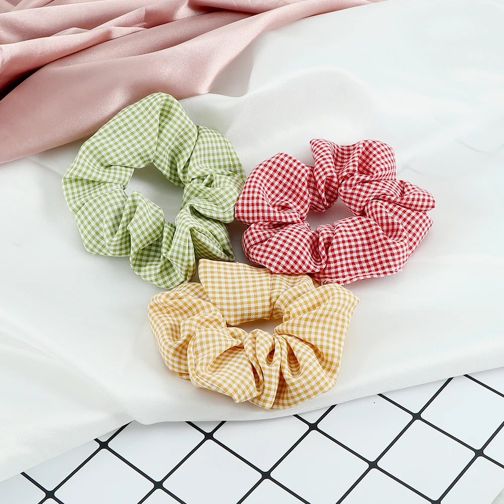 A set of three colorful knitted hair scrunchie headbands in pink, green, and yellow checkered patterns displayed on white fab