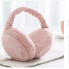 A soft pink plush fur ear warmer earmuff resting on a white surface.