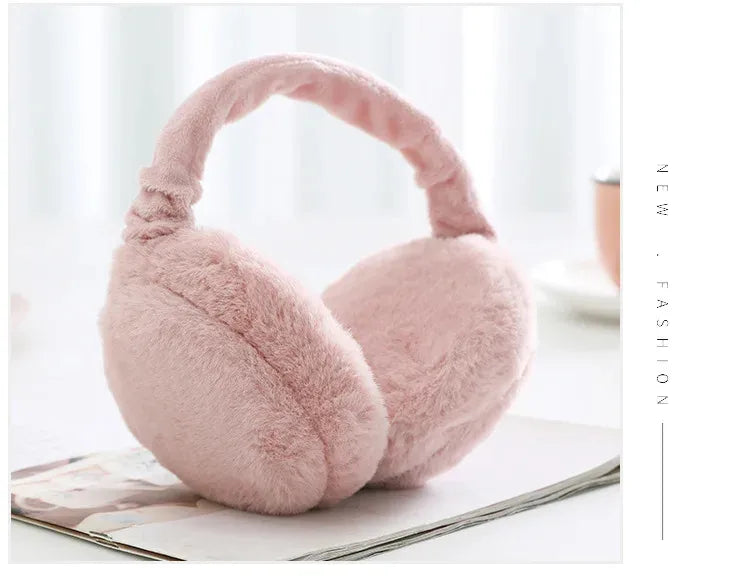 A soft pink plush fur ear warmer earmuff resting on a white surface.
