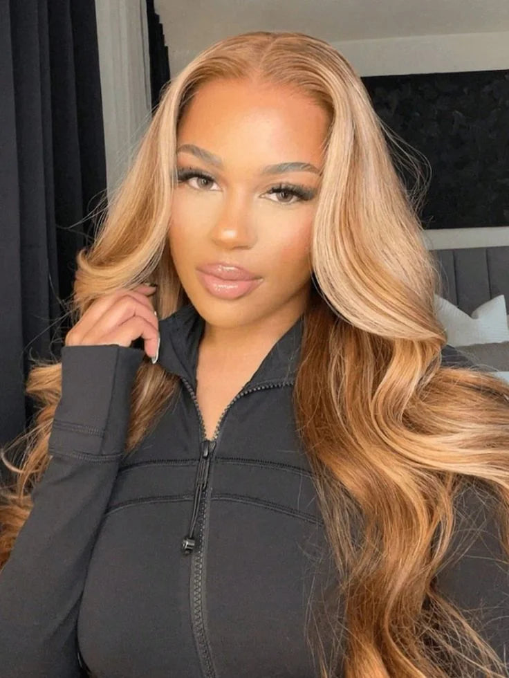 A woman with long, wavy honey blonde hair wearing a black zip-neck top.