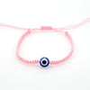 Pink string bracelet with a blue evil eye charm for protection
