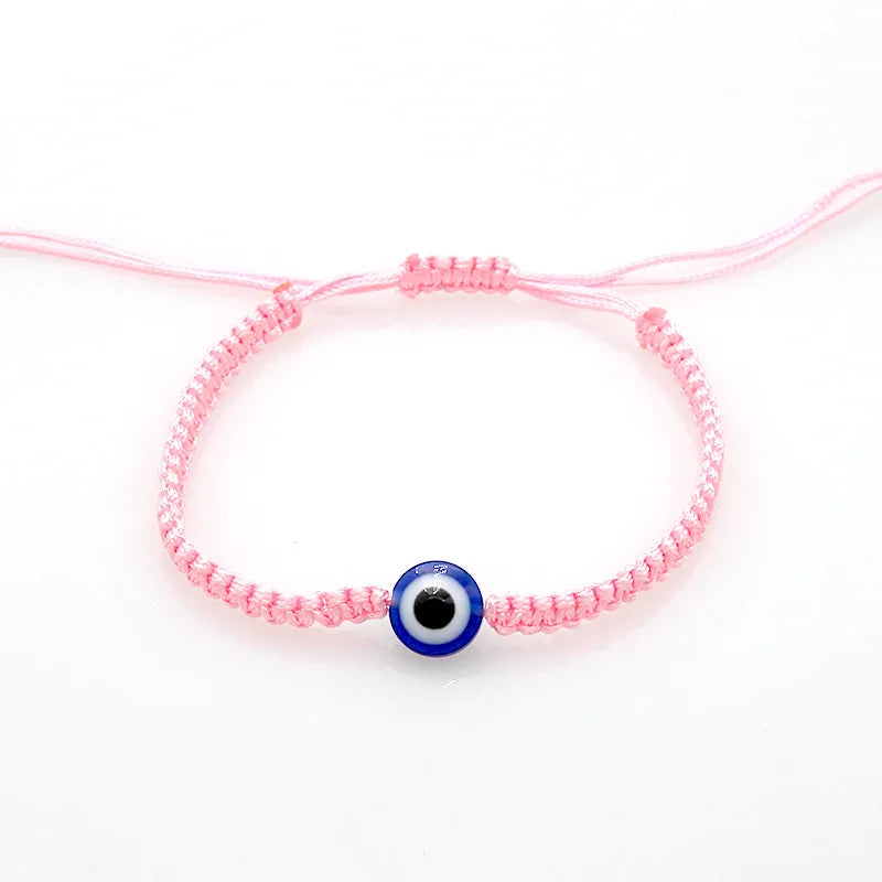 Pink string bracelet with a blue evil eye charm for protection