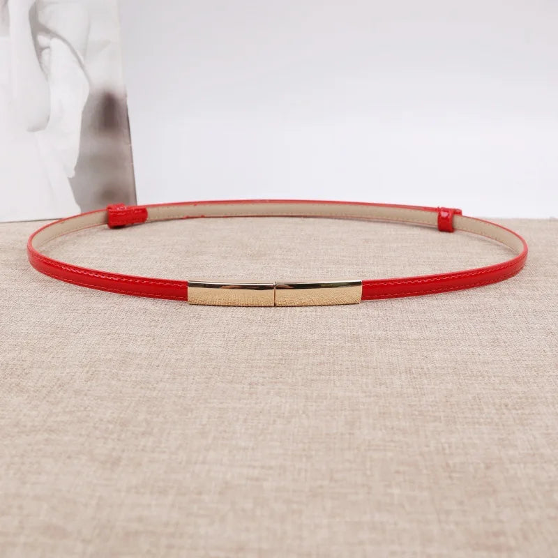 Riemen aus roter Leder mit goldener Schnalle auf beigem Untergrund.