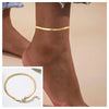 A close-up of a gold-toned snake chain anklet worn around the ankle of a person.