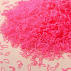 A pile of bright pink disposable rubber hair ties for kids scattered on a light surface.