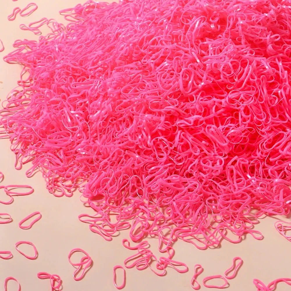 A pile of bright pink disposable rubber hair ties for kids scattered on a light surface.