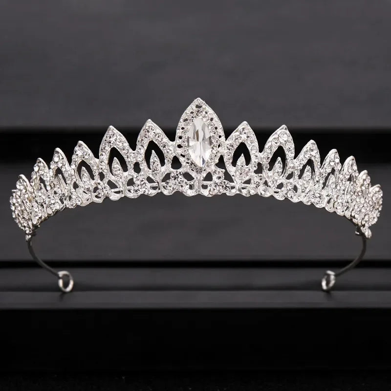A sparkling crystal bridal crown with a prominent central stone displayed on a dark surface.