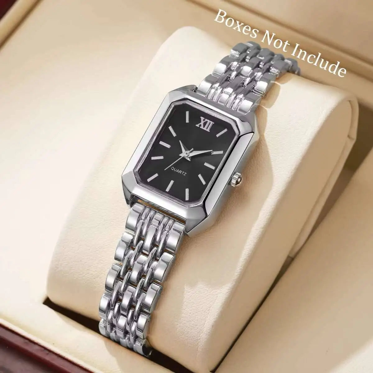 Reloj analógico de cuarzo plateado con esfera negra y pulsera de metal, mostrado en una caja beige clara.
