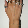 A hand wearing multiple gold and silver ball link finger bracelets.