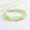 Pulsera hecha de cuentas blancas y verde lima pequeñas, apiladas en varias hebras.
