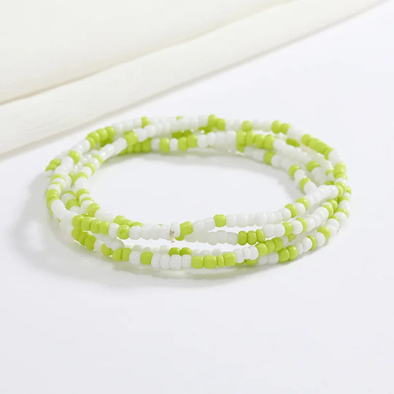 Pulsera hecha de cuentas blancas y verde lima pequeñas, apiladas en varias hebras.