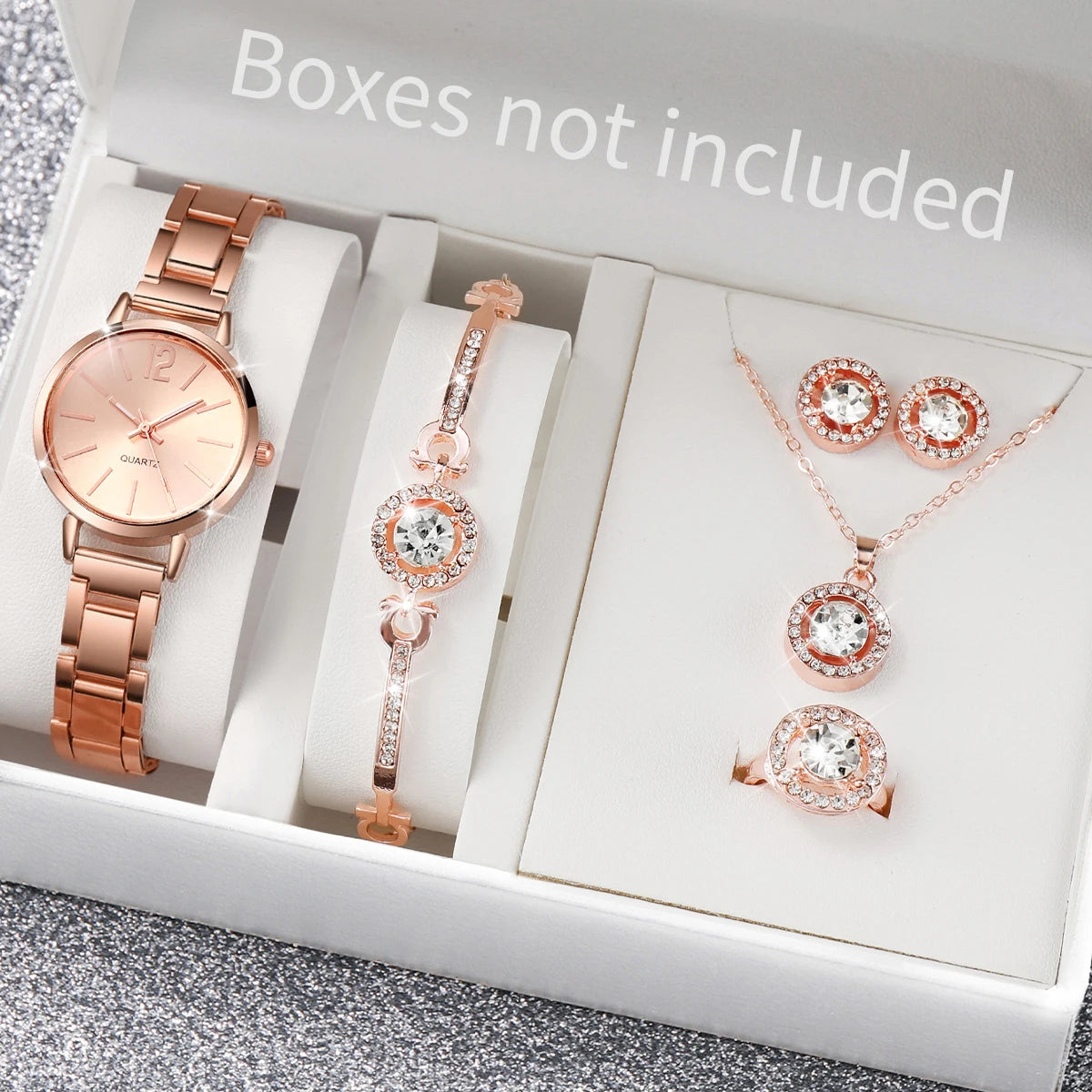A white box contains a rose gold quartz wrist watch, a pendant necklace, and a ring set.