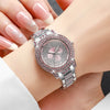 A close-up shot of a silver watch with pink accents and diamond rhinestones worn on a wrist.