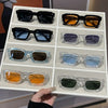 A collection of retro square fashion sunglasses in various colors and finishes displayed in a white tray.