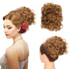 A woman shows off a synthetic curly chignon hairstyle, featuring reddish-brown curls and volume.