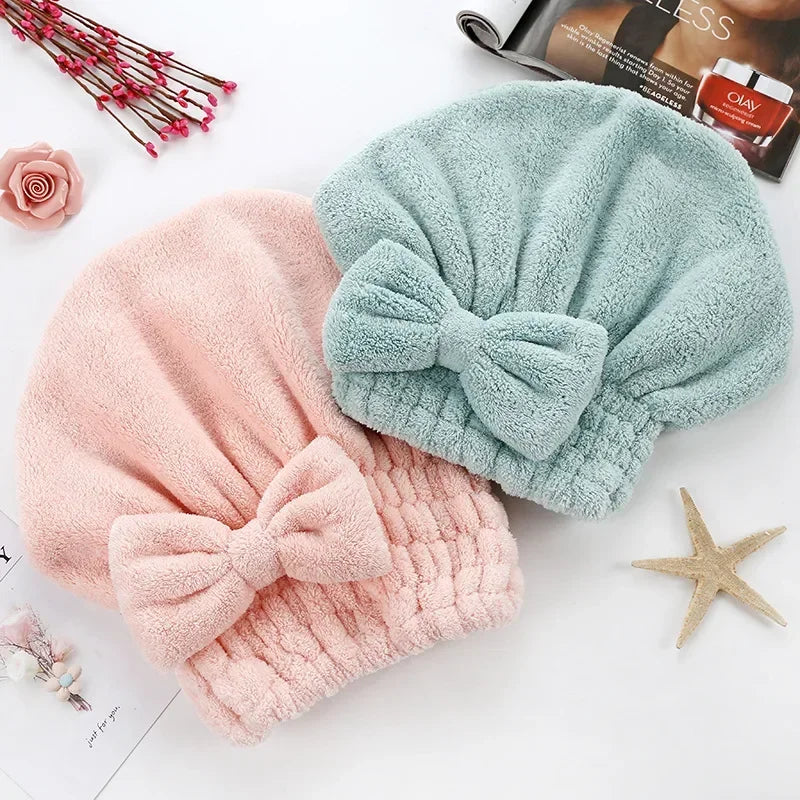 A pink microfiber hair drying towel and a mint green microfiber hair drying towel are displayed on a white background.
