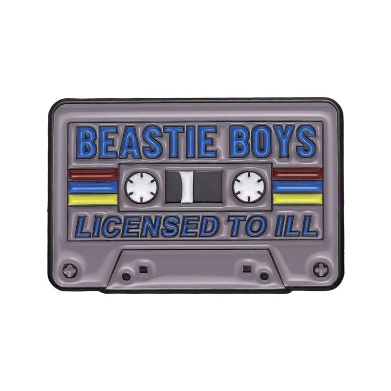 A rectangular enamel pin featuring the text BEASTIE BOYS LICENSED TO ILL in blue and yellow lettering on a gray background.