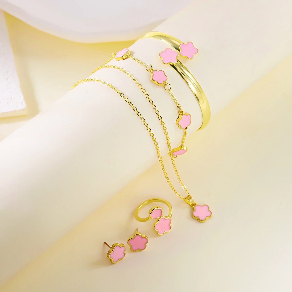 A set of five gold-toned bracelets featuring pink enamel plum blossom charms displayed on a light background.
