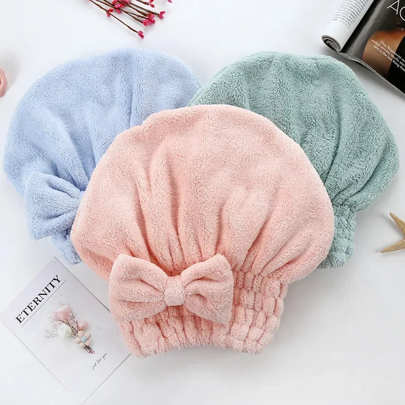 Three fuzzy microfiber hair drying towels in blue, green, and pink are displayed on a white surface.