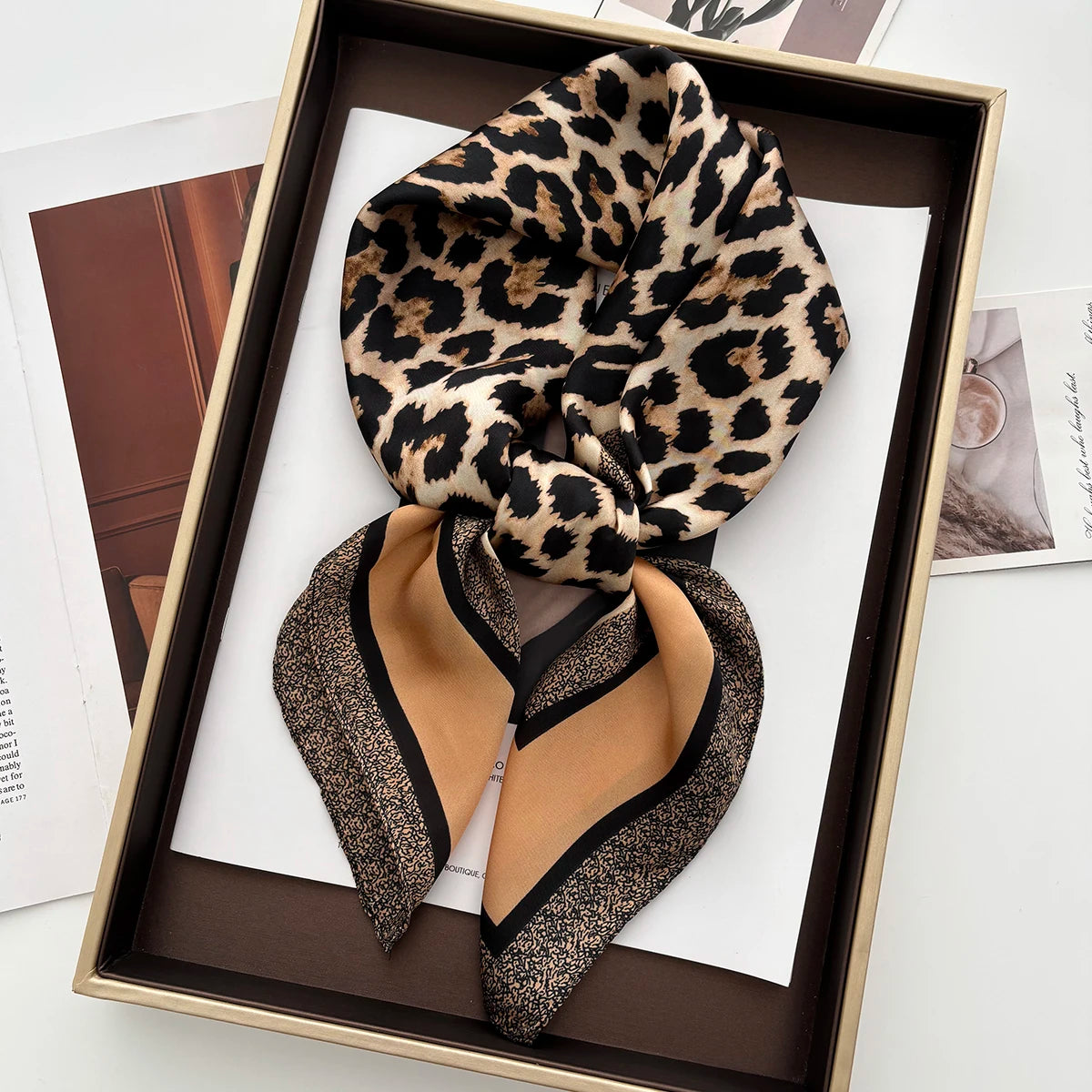 A pair of black heeled sandals is displayed in a wooden box alongside a leopard print silk scarf.