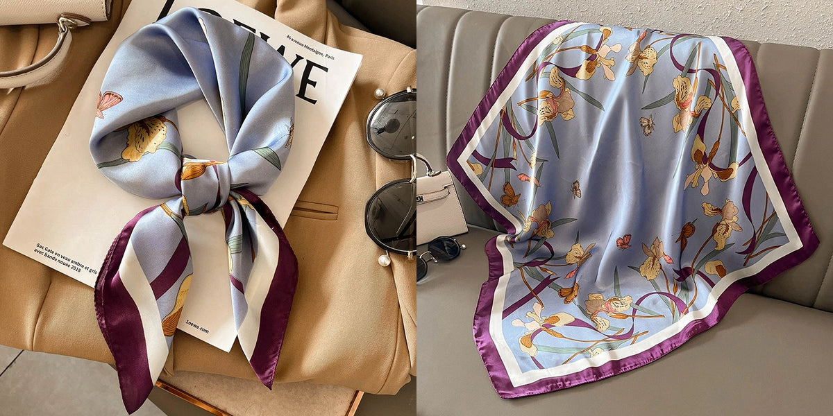 A light blue silk scarf with a floral print and purple trim is displayed on a beige garment.