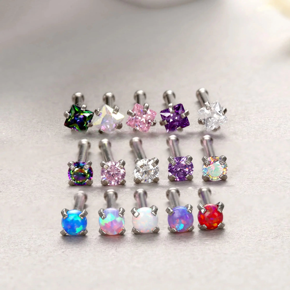A collection of surgical stainless steel nose piercing studs featuring various colored gemstones including green, pink, purpl
