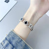 A close-up of a silver diamond four-leaf clover watch strap for a Xiaomi Mi Band worn on a wrist.