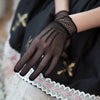 A hand wearing black fishnet lace evening gloves is visible against a dark fabric background.