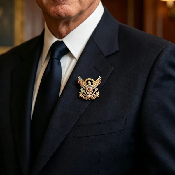 A close-up of a man wearing a dark suit and tie with a patriotic anniversary lapel pin brooch on his jacket.