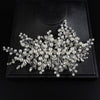A delicate bridal headpiece featuring white pearls and clear rhinestones arranged in a floral spray.