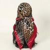 A black and gold leopard print satin silk scarf tied around a dark hairstyle.