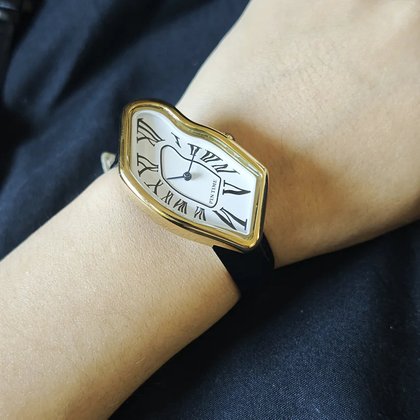 A close-up of a vintage irregular quartz watch with a gold-toned case and white face worn on a person's wrist.