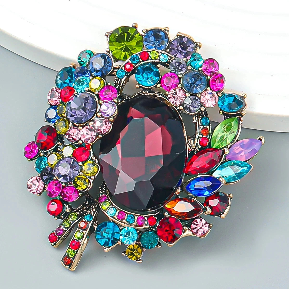 Broche florale en cristal élégante avec un cluster de pierres colorées (rose, bleu, vert et violet).