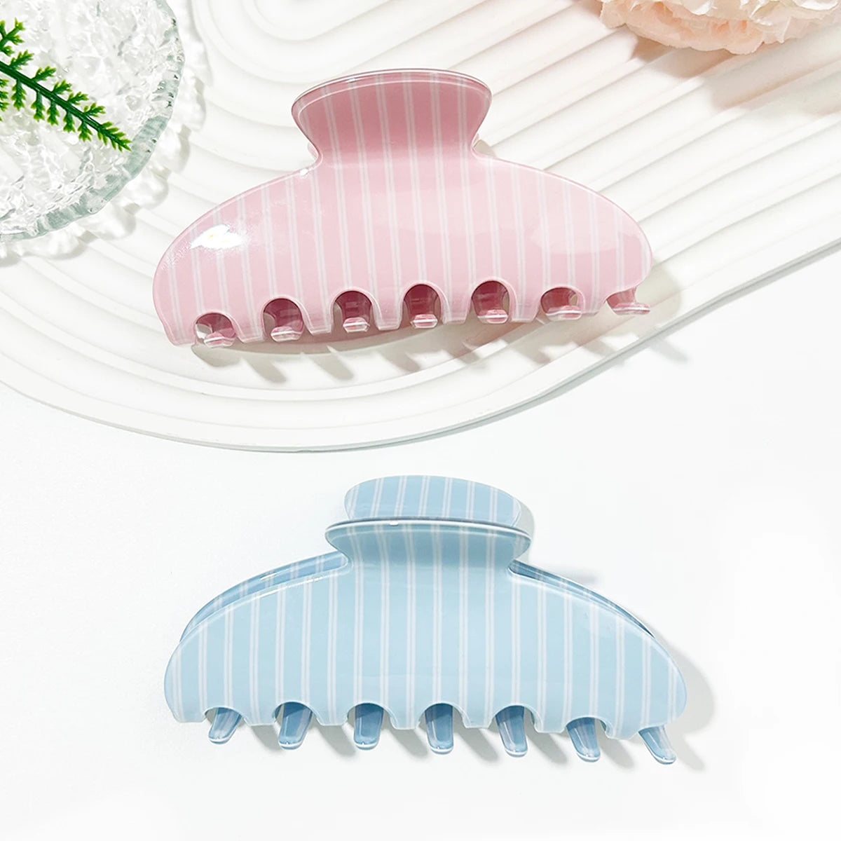 A set of pink and blue striped plastic hair clips resting on a white plate.