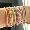 A stack of colorful beaded bangles worn on a wrist, featuring various shades of pink, orange, yellow, and blue.