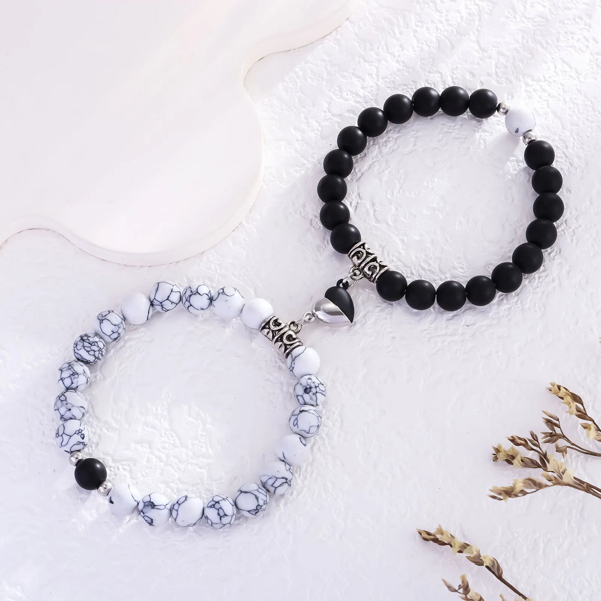 A set of natural stone heart couple bracelets featuring black and white marbled stones.