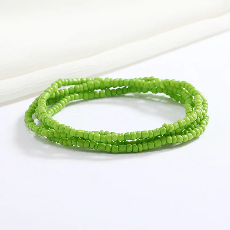 Pulsera de cadena corporal de cuentas verdes sobre una superficie blanca.