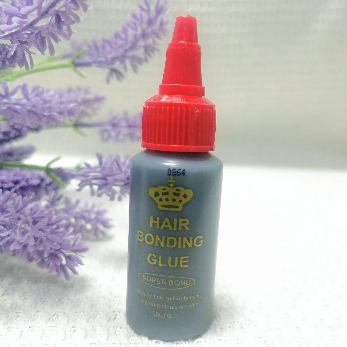 A bottle of Hair Bonding Glue with a red cap and gray body is shown next to purple lavender flowers.